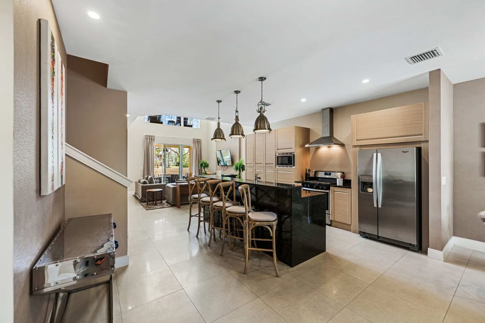 Modern kitchen with a black granite island and stainless steel appliances overlooking the living area.