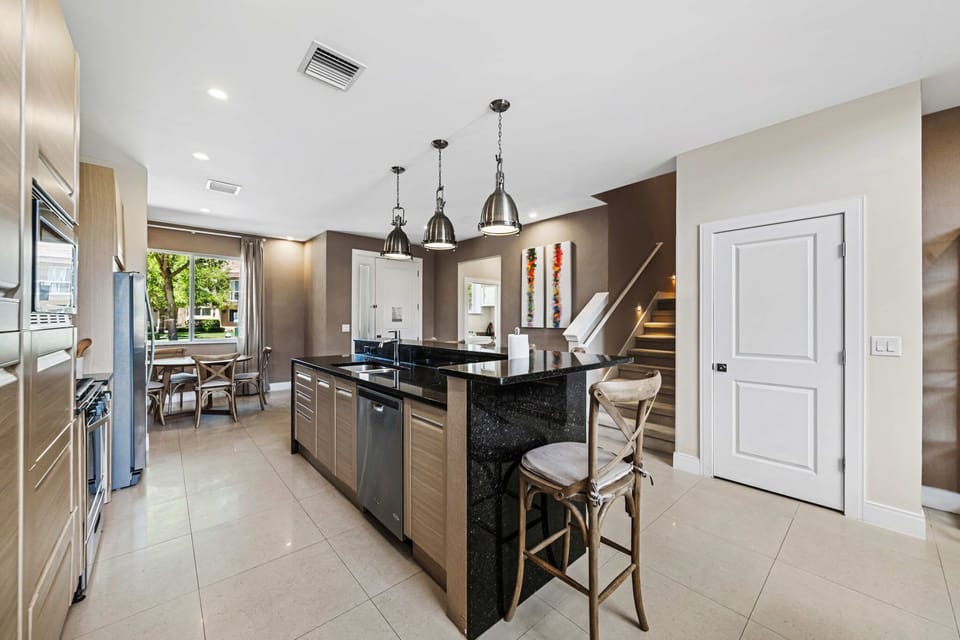 Modern kitchen with a large black granite island and industrial pendant lighting