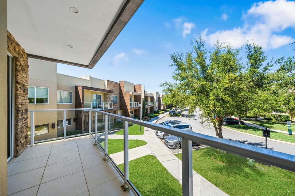 Modern balcony overlooking a tree-lined street and residential buildings