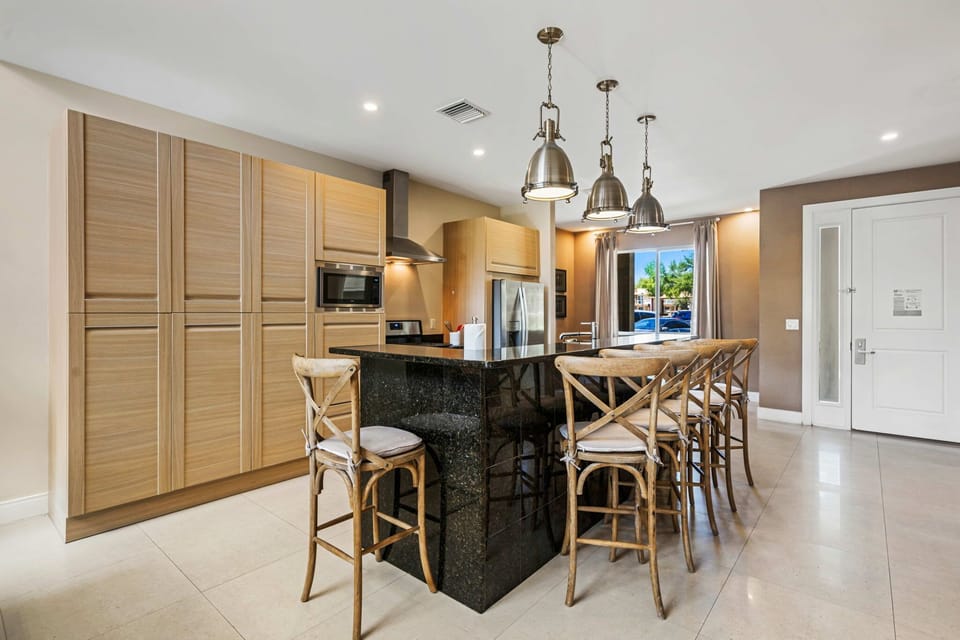 Modern kitchen with a large black granite island and wooden bar stools for casual dining.