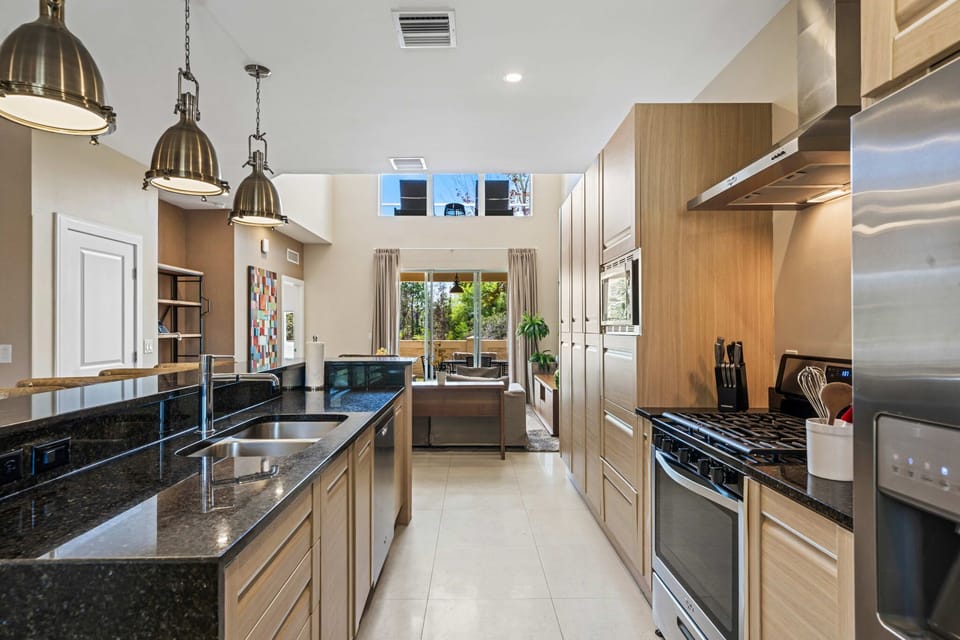 Modern kitchen with granite countertops and stainless steel appliances overlooking the living area.