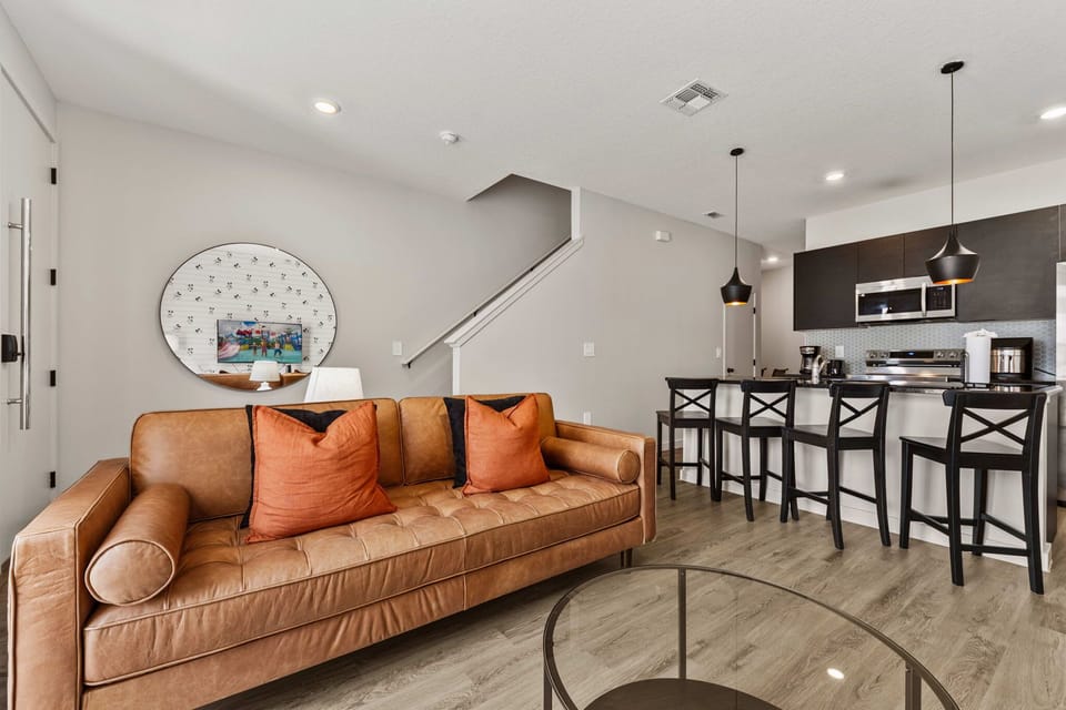 Modern living area with leather sofa and open kitchen featuring a breakfast bar.