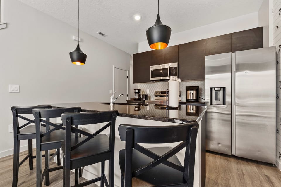 Modern kitchen with black cabinetry, stainless steel appliances, and a breakfast bar with seating.