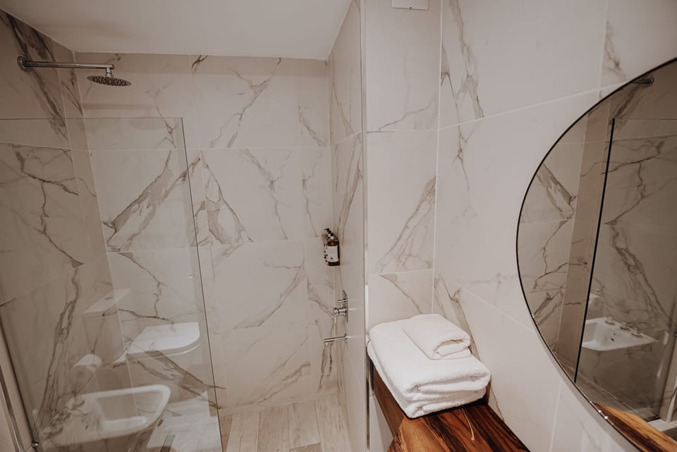 Refresh under a rainfall shower in sleek marble surrounds.