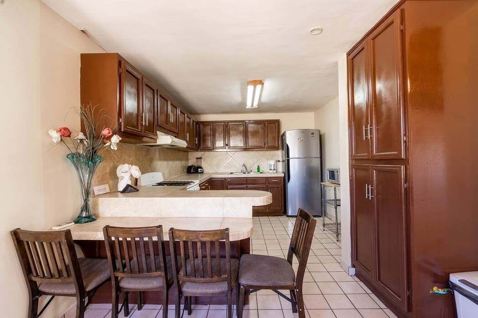 The spacious kitchen features a 4-burner stove with oven, microwave, full-size refrigerator, coffee maker, and dishes for 10 — perfect for group meals just steps from the beach