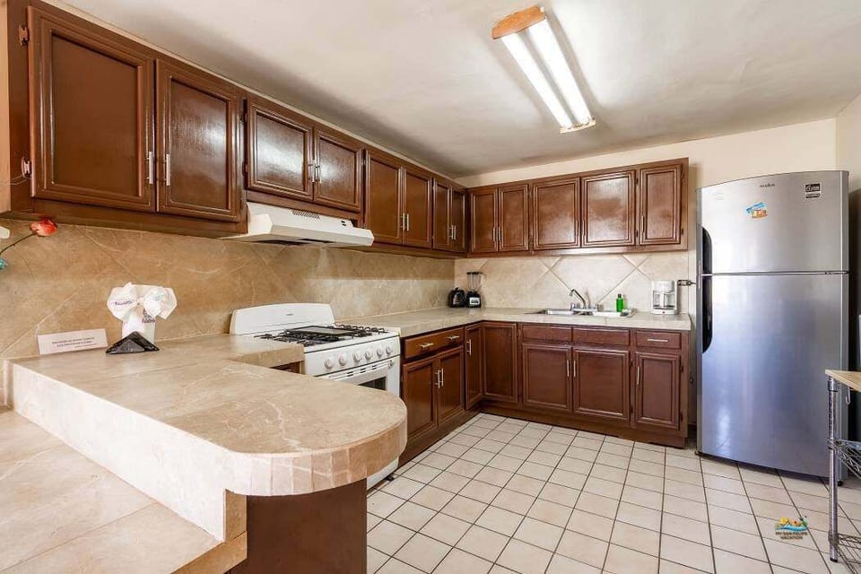 The spacious kitchen features a full-size refrigerator with freezer, 4-burner stove, oven, microwave, coffee maker, and dishes for 10 — perfect for group meals just steps from the beach .