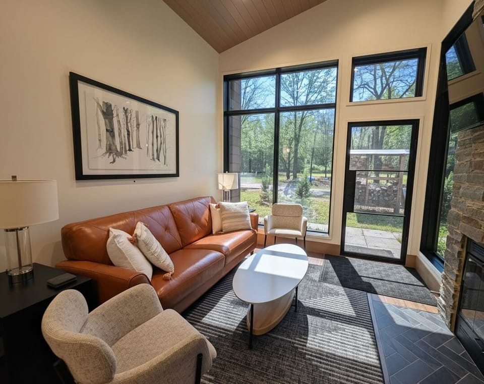 Living room with wood burning fireplace and floor to ceiling windows