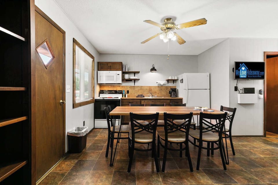 Wide kitchen and dining with live-edge table, full appliances, and flat-screen TV