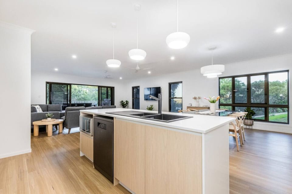 Spacious kitchen and living area featuring island with dual sink, comfortable sofas, and dining space for family gatherings.