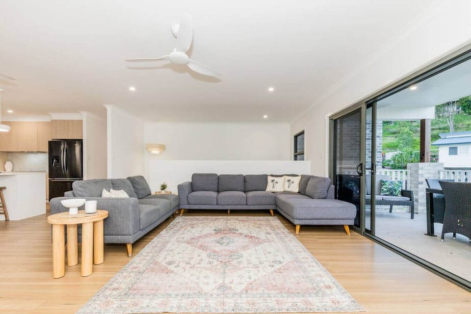 Comfortable lounge featuring large sectional sofa, open kitchen, and patio access — perfect for family gatherings.