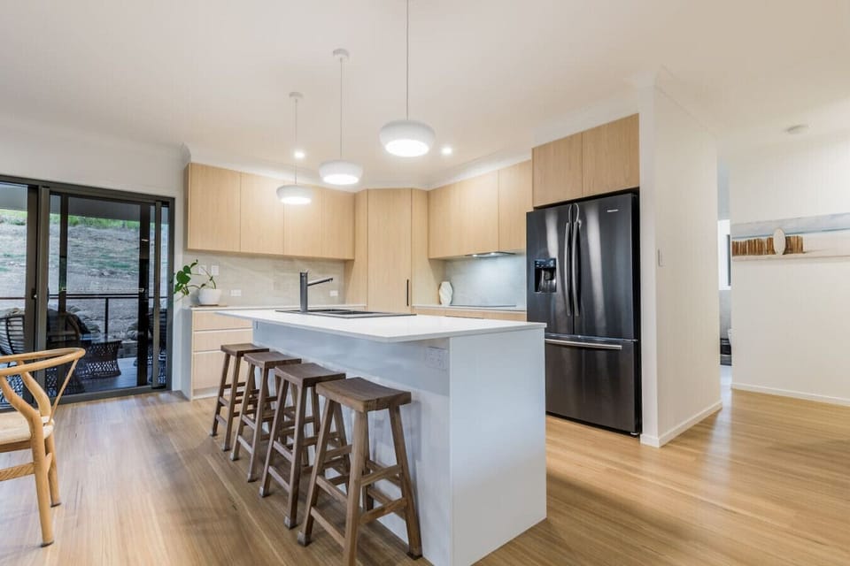 Spacious kitchen featuring island with bar stools, modern appliances, and patio access for family cooking and gatherings.
