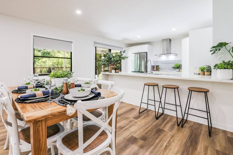 Modern kitchen with stainless appliances, timber dining table set for six, and bar stools. Family‑friendly dining and entertaining space.