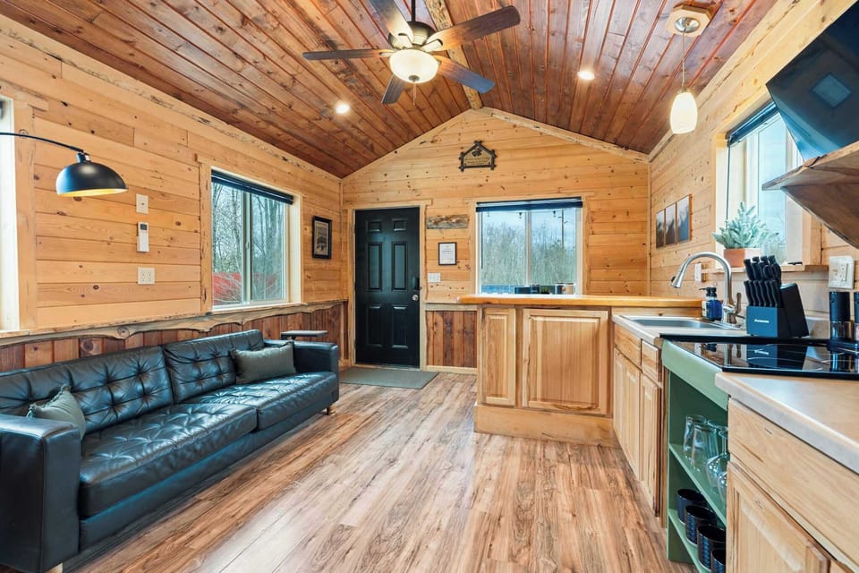 Open-concept living space with vaulted pine ceilings and leather sofa.