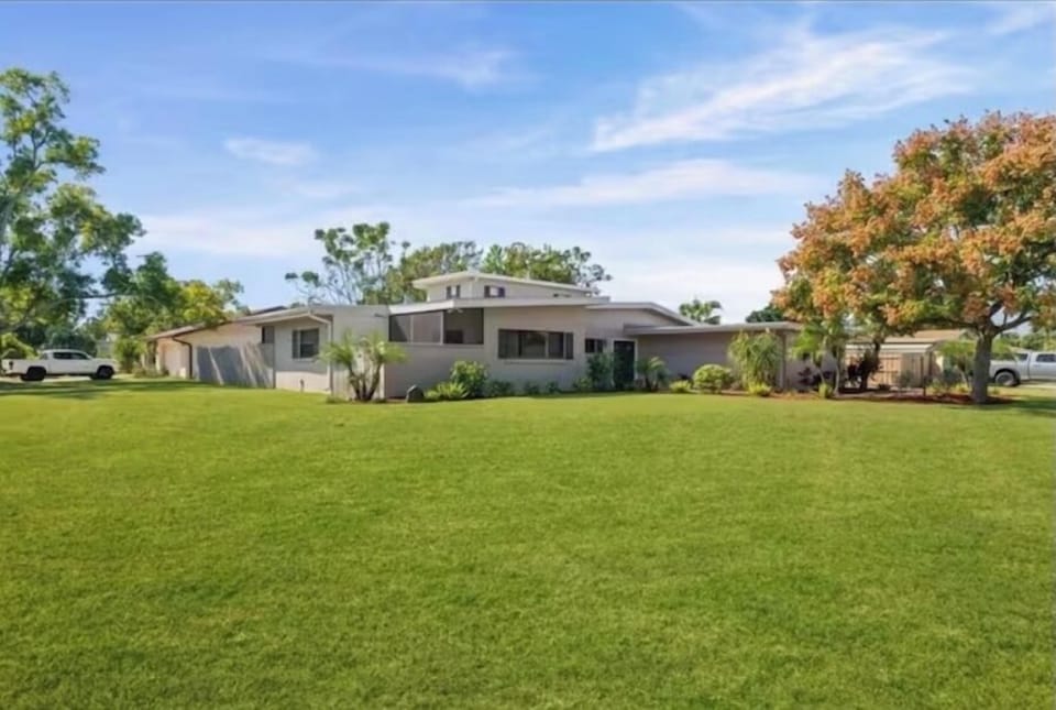 Front view of the home with large driveway and green yard.