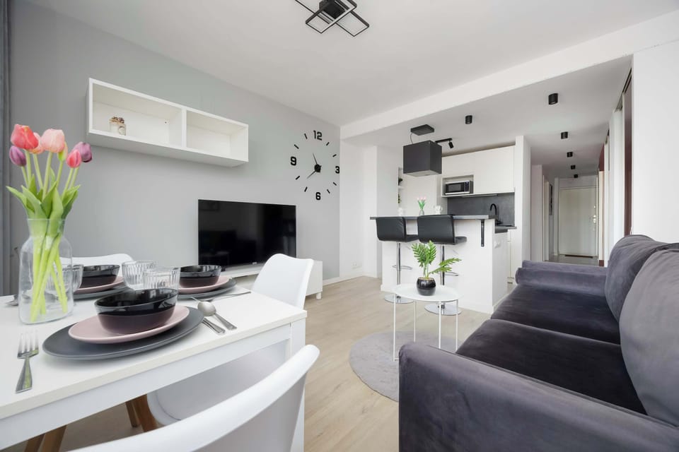 Another angle of the living room with a sofa, coffee table, and TV. The open layout connects seamlessly with the kitchen area. The interior remains bright and cohesive.