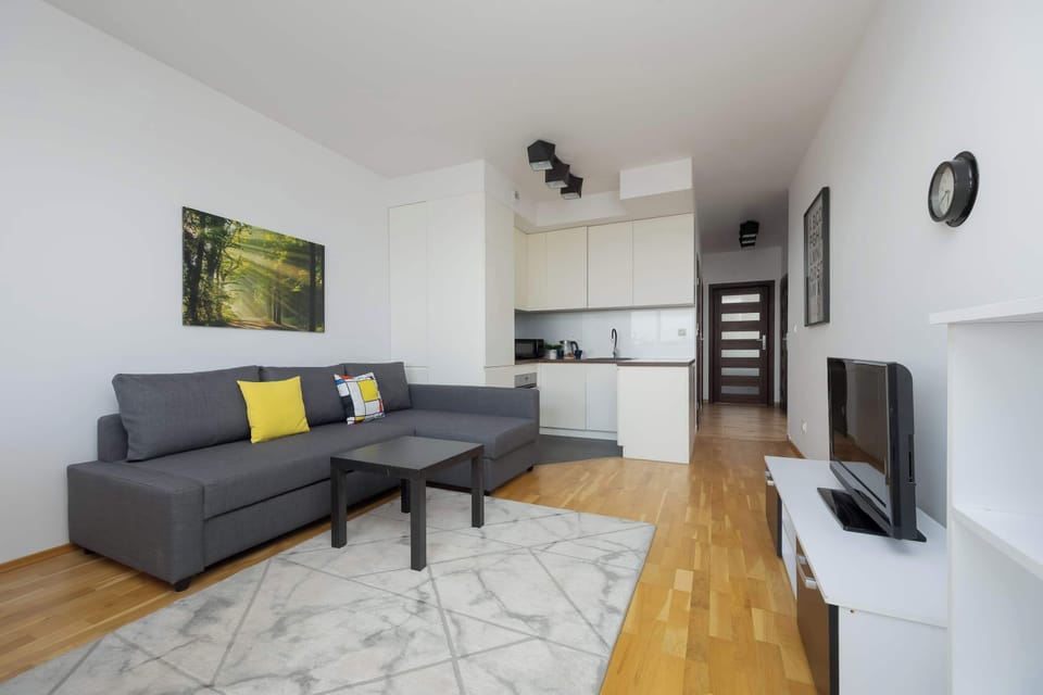 A view toward the entrance shows the kitchenette area and the hallway leading to other parts of the apartment. The clean lines of the white cabinetry maintain a streamlined and tidy appearance.