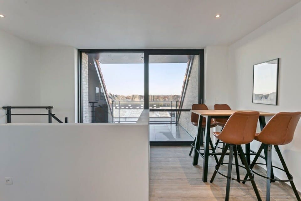 Modern dining area with leather chairs and balcony access offering natural light.