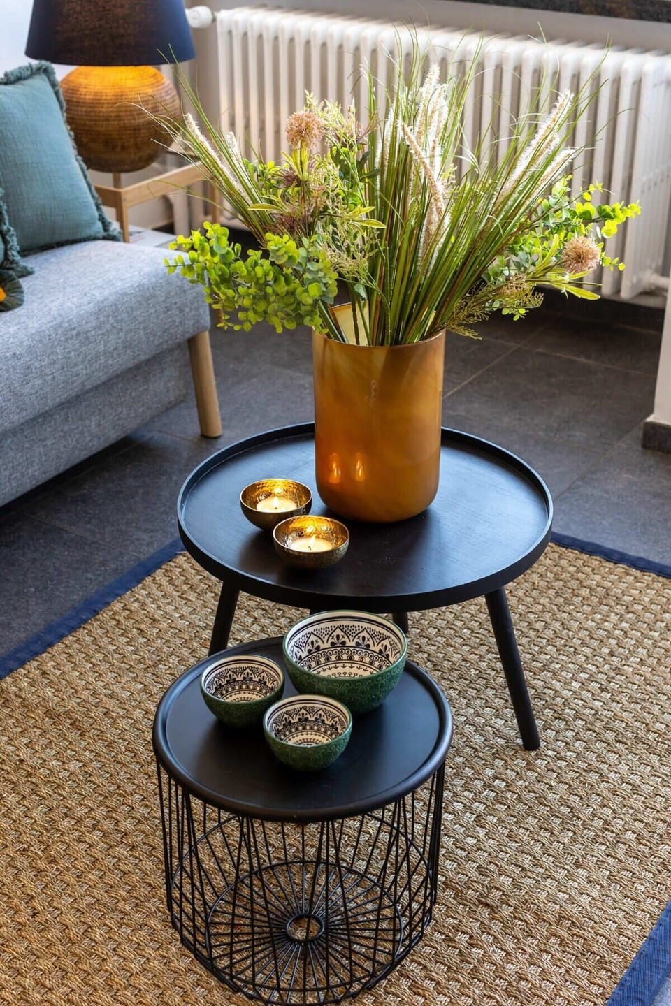 Modern black nesting tables with decorative bowls and a floral centerpiece create a cozy living space.