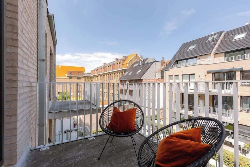 Cozy balcony seating with views of surrounding modern buildings.