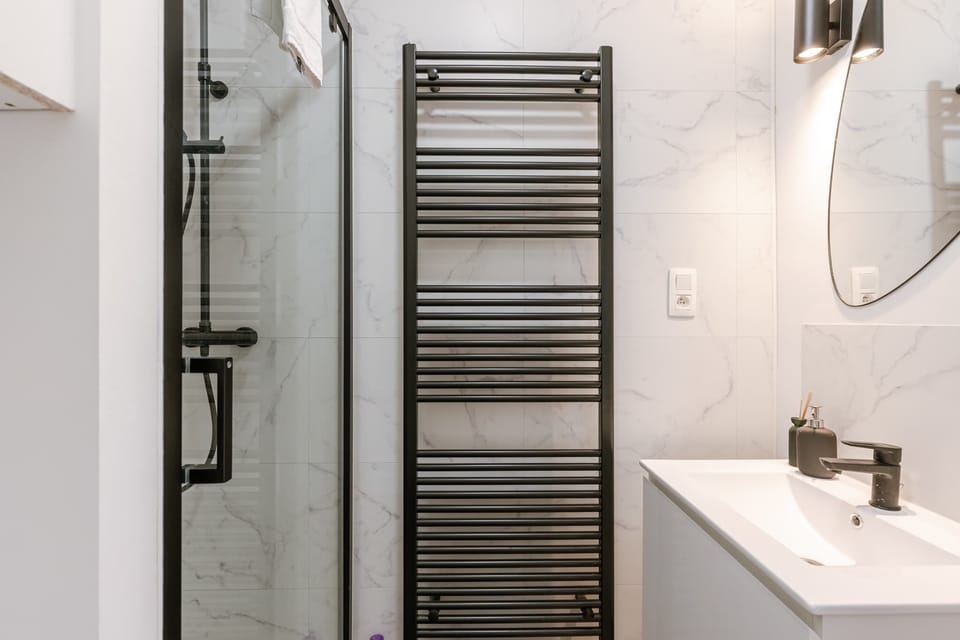 Modern bathroom featuring a black heated towel rack and glass shower enclosure