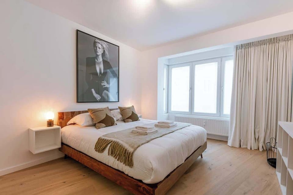 Modern bedroom with natural light and minimalist decor featuring a wooden bed frame and stylish artwork.
