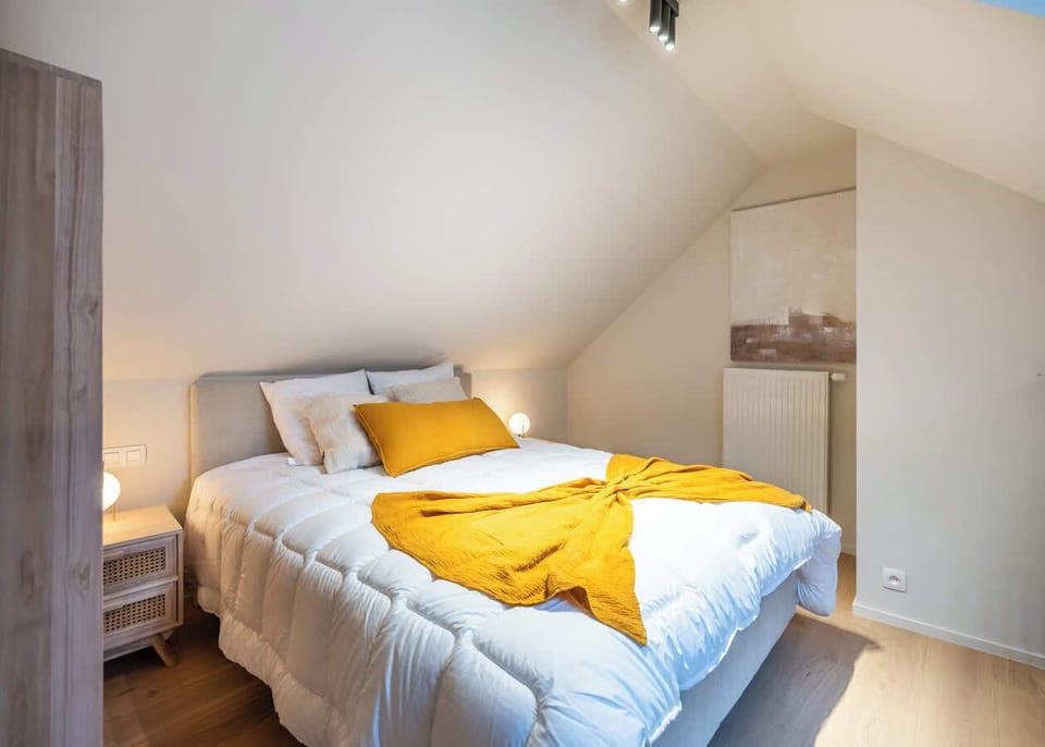 Cozy bedroom with sloped ceilings and warm yellow accents for a relaxing stay.