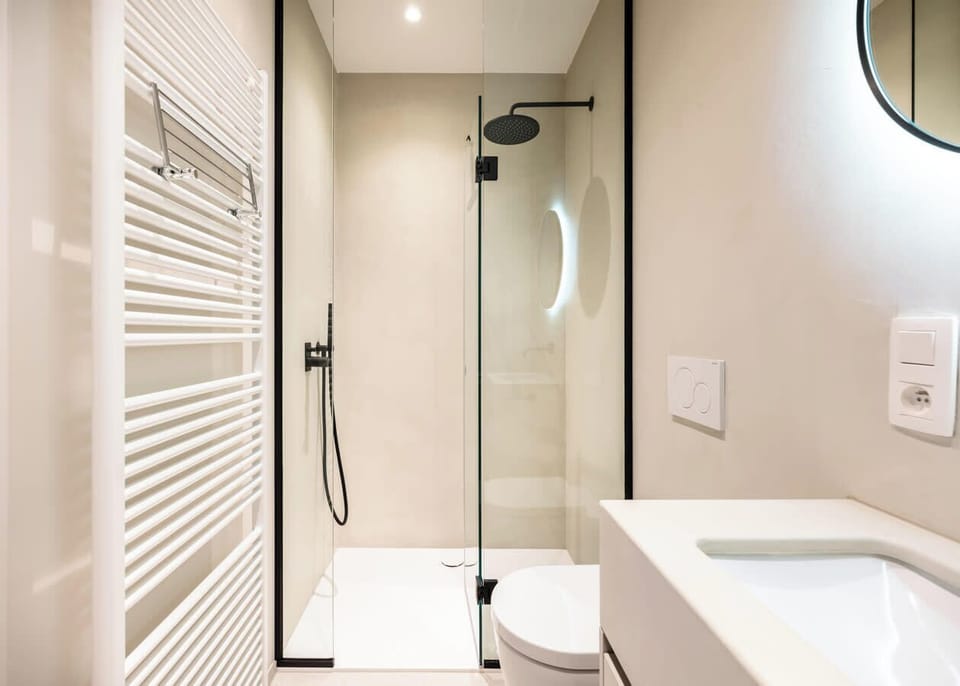 Modern bathroom with a walk-in shower and illuminated mirror.
