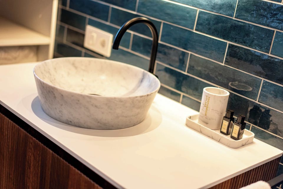 Modern bathroom sink with a marble basin and blue tiled backsplash