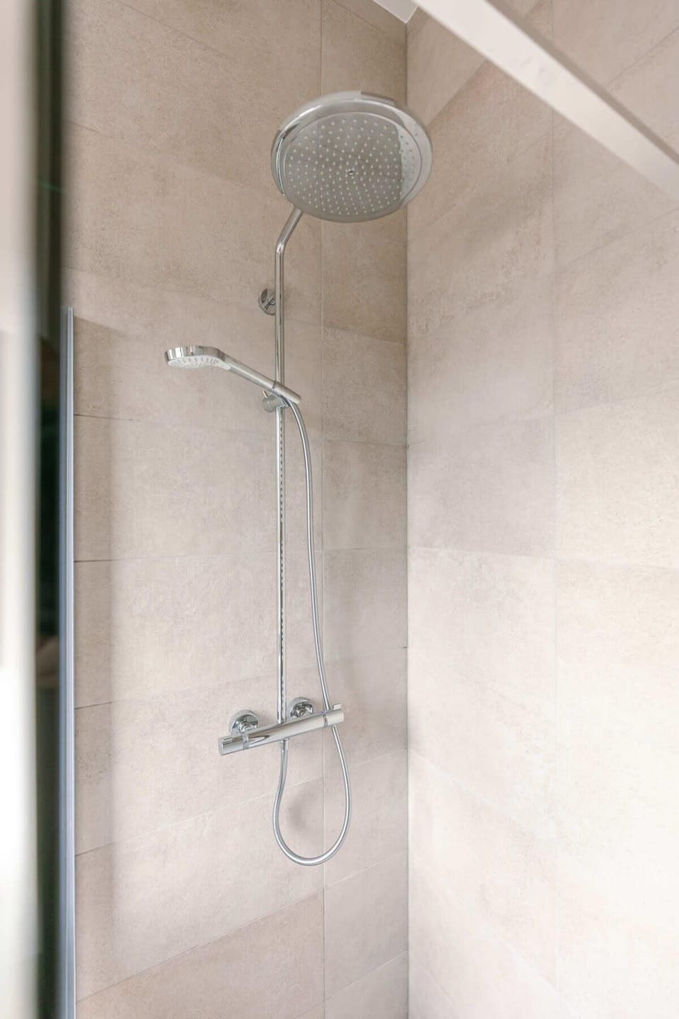 Modern shower with dual showerheads and neutral tile walls