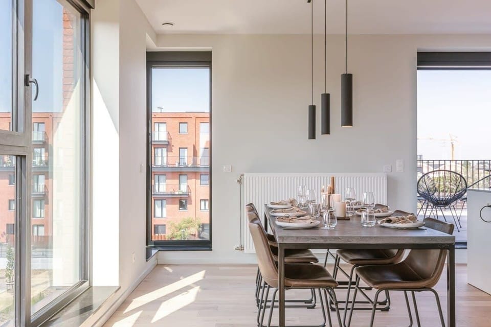 Modern dining area with a large table set for six and natural light from floor-to-ceiling windows.