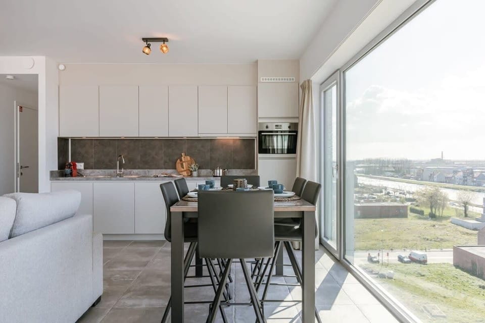 Modern kitchen and dining area with large windows offering a bright view.