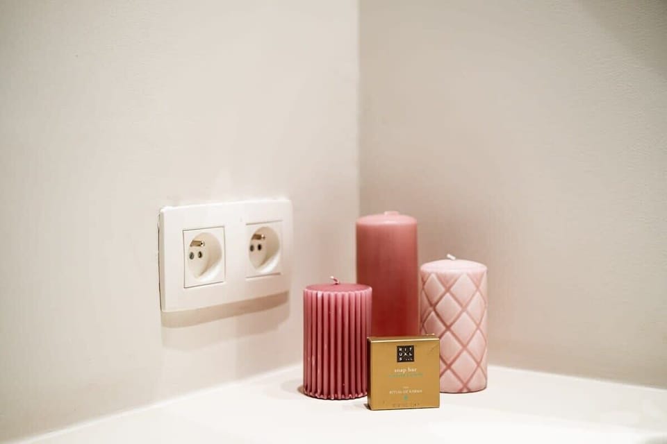 Decorative pink candles and a soap bar add a cozy touch to the bathroom corner.