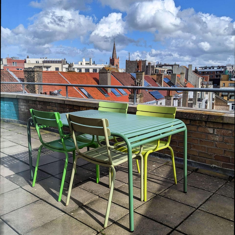 Outdoor terrace with colorful seating and city skyline views including a church steeple.