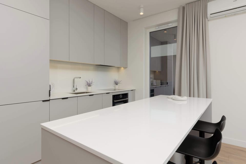 A sleek kitchen with white cabinetry, a long island counter, and modern appliances integrated into the design.