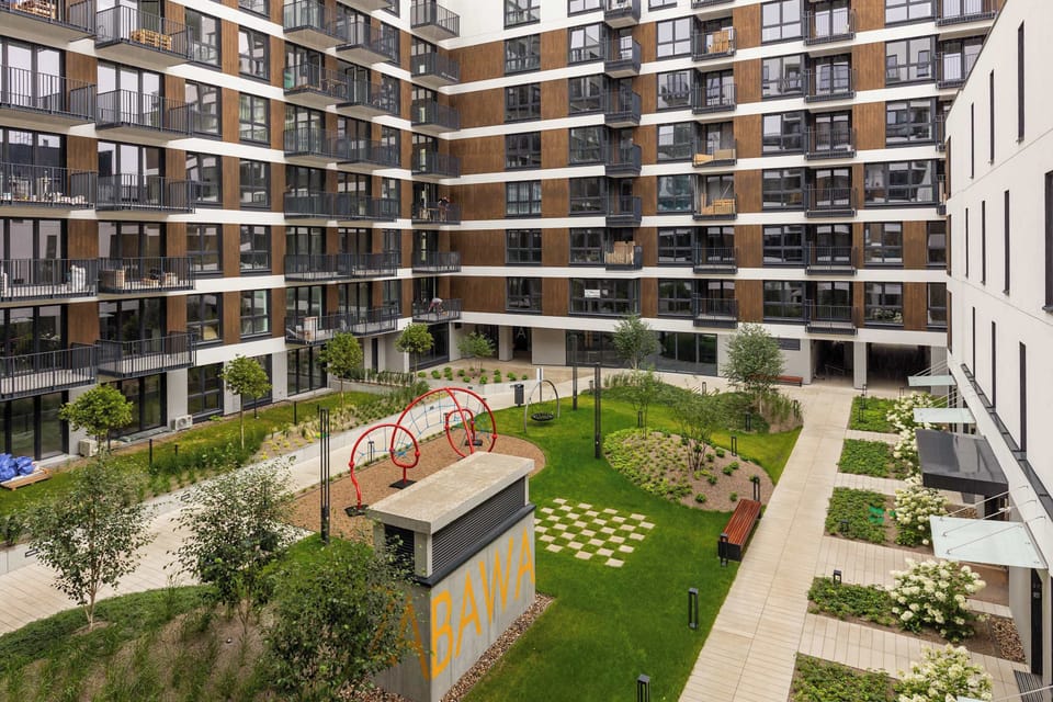 A landscaped inner courtyard surrounded by apartment buildings, with greenery and a central seating area.
