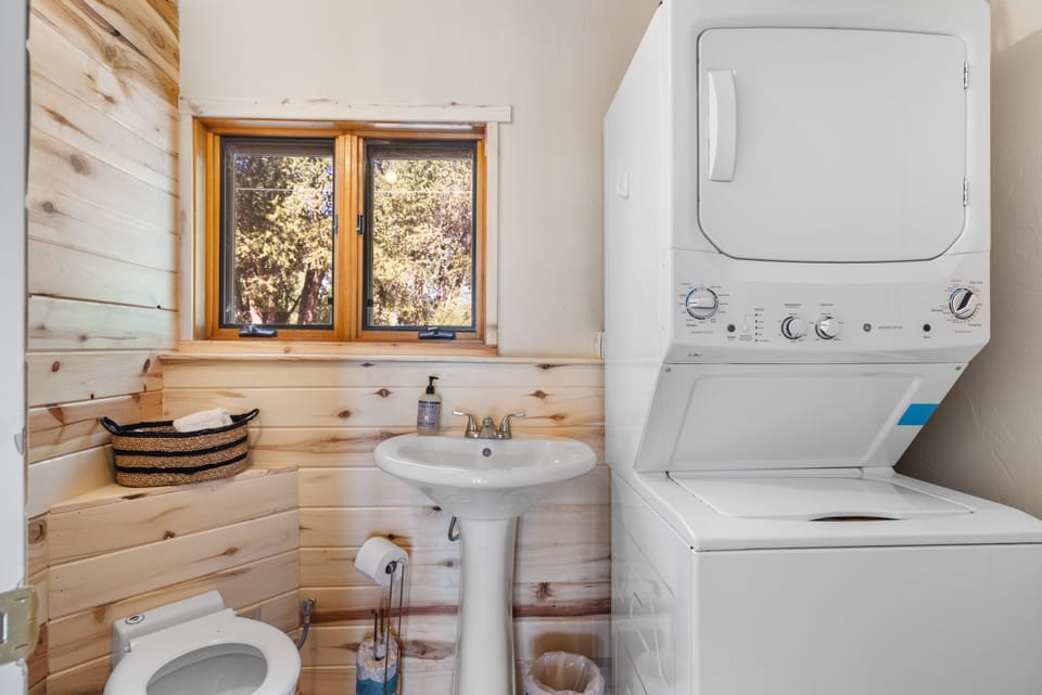A bathroom and laundry area with a pedestal sink and stacked washer-dryer.