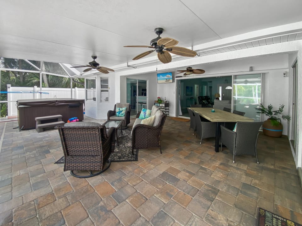 Spacious patio with hot tub and ceiling fans, perfect for outdoor relaxation and dining.
