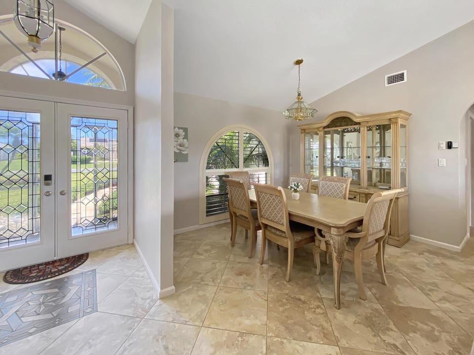 Elegant dining room with large windows and a stylish glass cabinet.