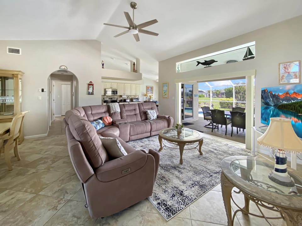 Spacious living area with plush seating and pool views, perfect for relaxation and entertaining.