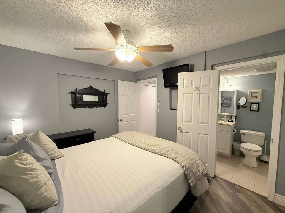 The bedroom retreat showcases a plush queen bed, ensuite bath, & TV​