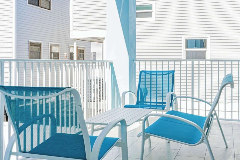 Settle into your private balcony where coastal breezes and bright turquoise seating create the perfect morning coffee spot, just steps from neighboring beach homes.