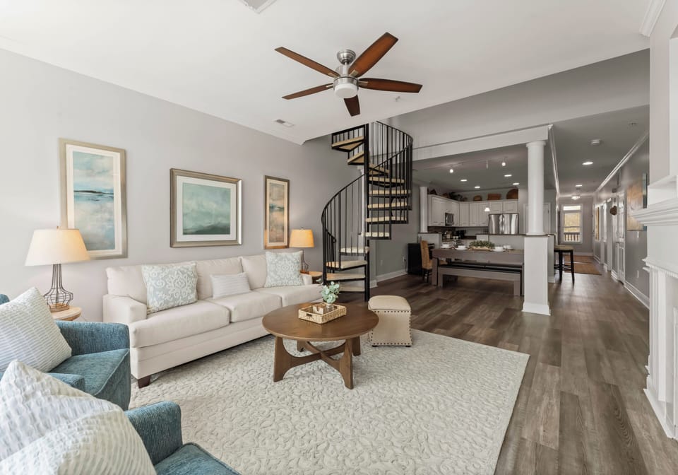 Living room with sliders to deck, couch, 2 chairs, TV & gas fireplace.