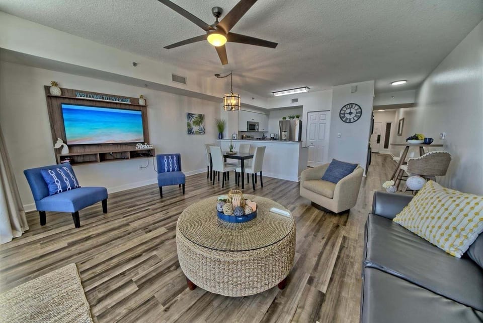 Open concept living area with stylish furnishings and huge TV + balcony access