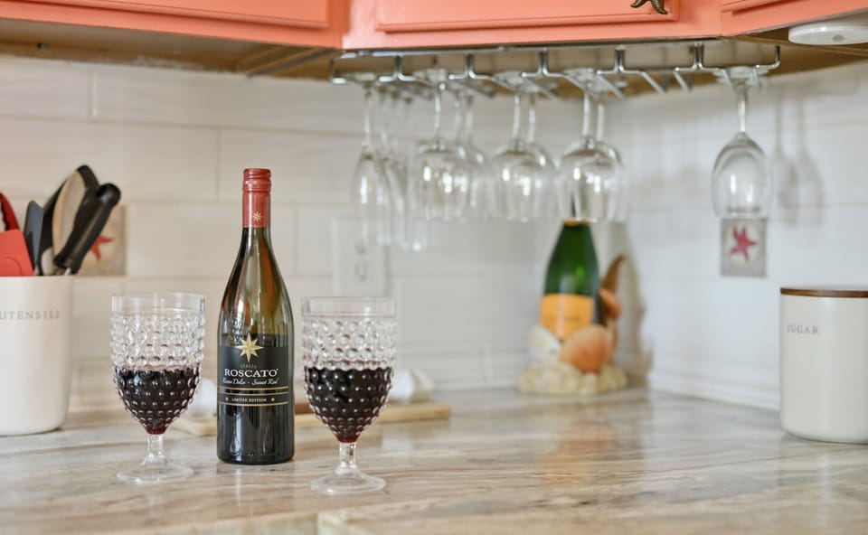 Kitchen Counter — Wine & Glasses with Hanging Stemware Under Coral Cabinets