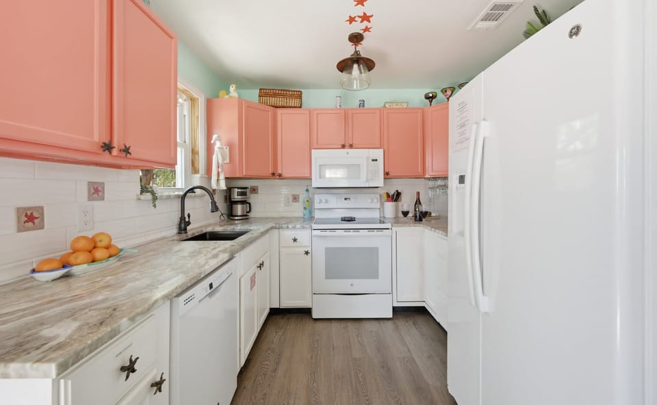 Kitchen — Coral Pink Cabinets, White Appliances & Starfish Tile Accents