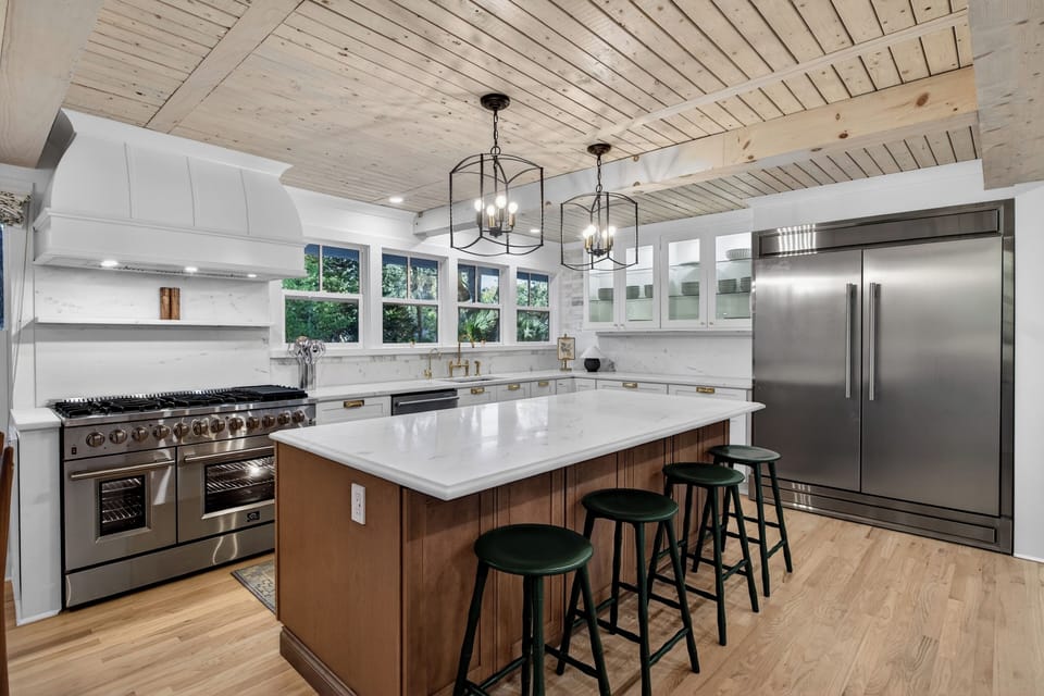 Bright modern kitchen with a marble island, brass accents, and warm wood details.