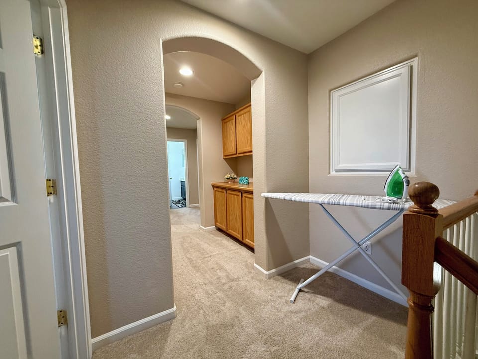 Upstairs hallway with storage, ironing area, and bright open layout.