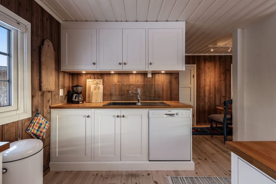 Kitchen nook with white cabinetry, wooden countertops, and warm ambient lighting.