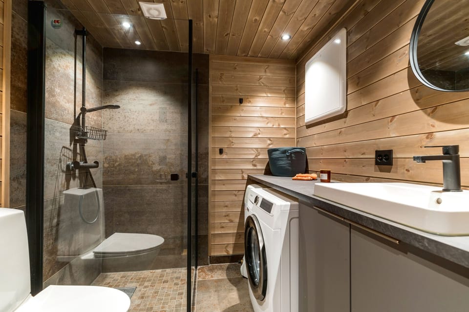 The bathroom has a shower and a washing machine.