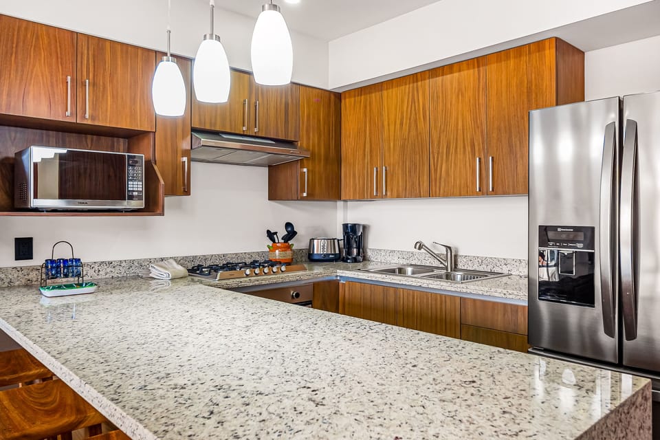 Modern kitchen featuring granite countertops, wooden cabinetry, and stainless steel appliances.